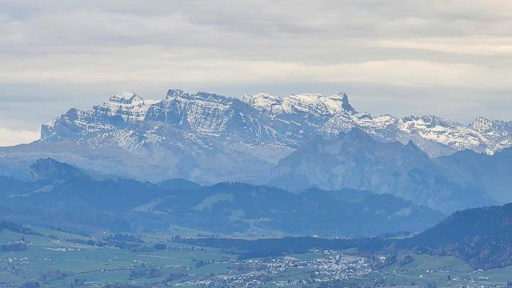 Chaîne de montagnes aux sommets enneigés sous un ciel nuageux.