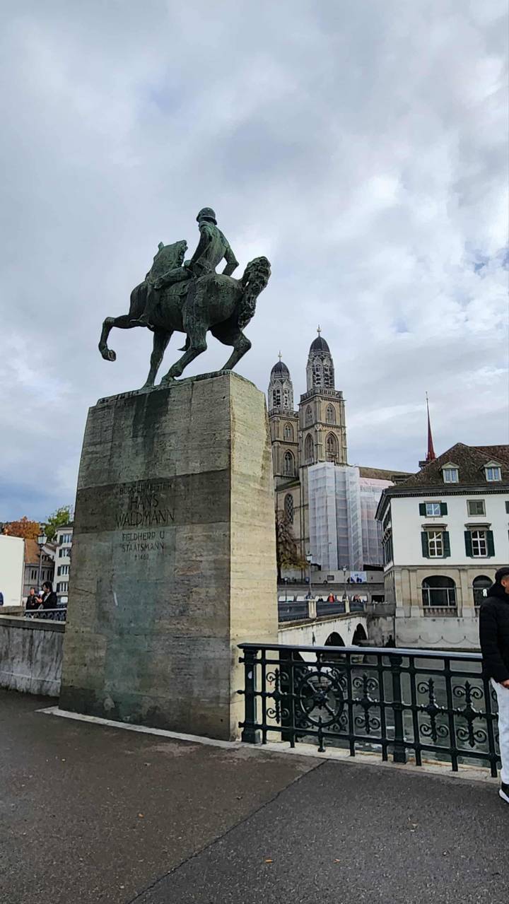 Statue d'un cheval et de son cavalier devant de grandes tours de cathédrale.