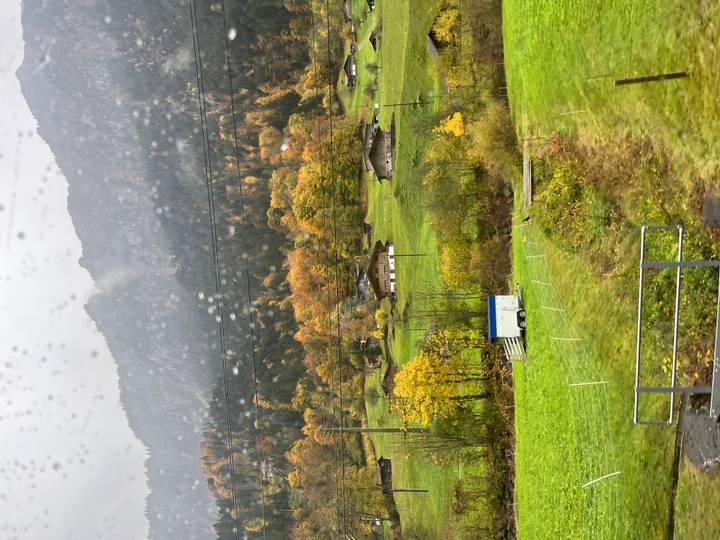 Paysage pittoresque avec des champs verts, des collines et un ciel nuageux.