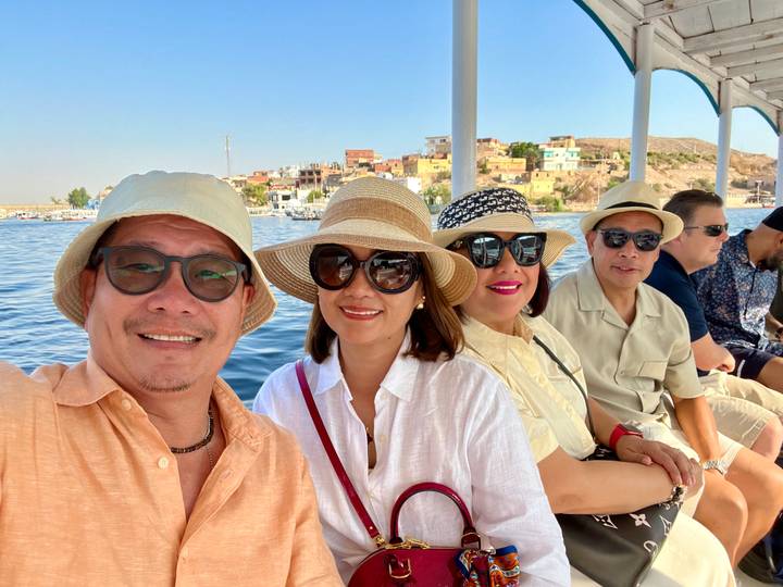 Des personnes lors d'une promenade en bateau avec vue sur des bâtiments au bord de la rivière.