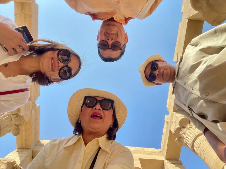 Des gens qui regardent vers le haut en direction d'une caméra, avec un ciel bleu en arrière-plan.