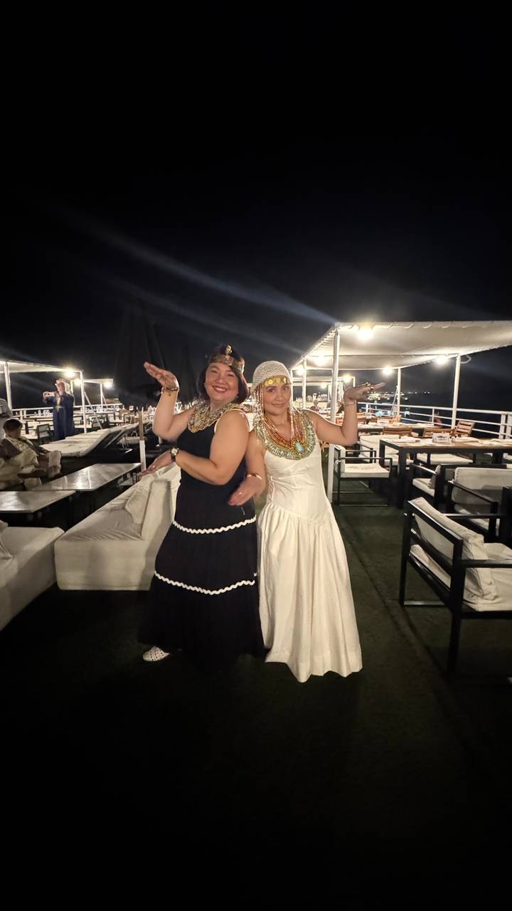 Deux personnes posant en tenues traditionnelles lors d'une croisière fluviale nocturne.