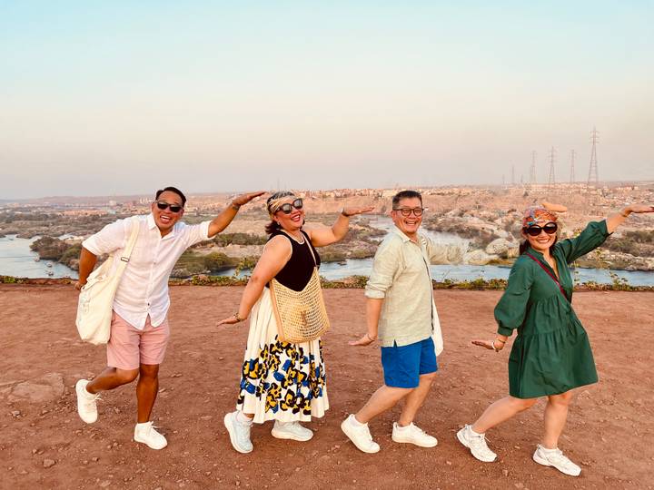 Quatre personnes posant avec une vue panoramique sur une rivière et une ville.