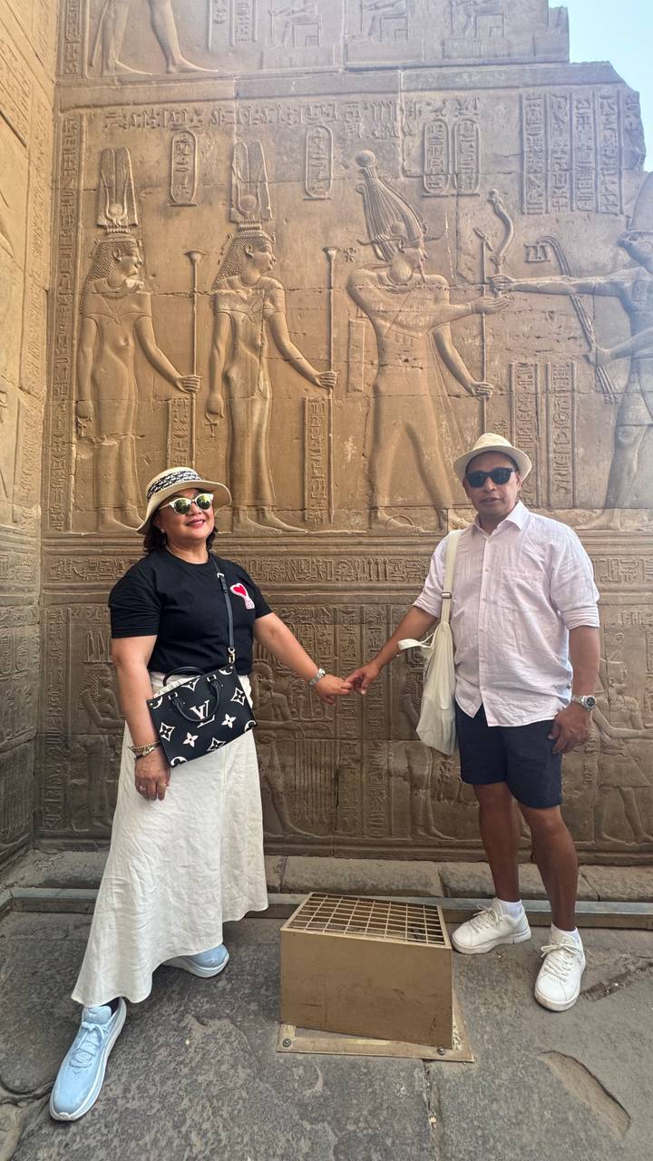 Deux personnes debout devant des sculptures égyptiennes antiques.