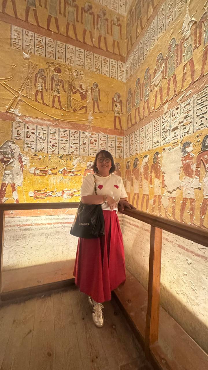 Visiteur à l'intérieur d'un tombeau avec de l'art mural égyptien antique coloré.