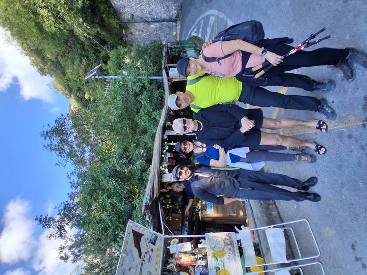 Groupe de randonneurs debout devant un petit magasin dans une zone boisée.