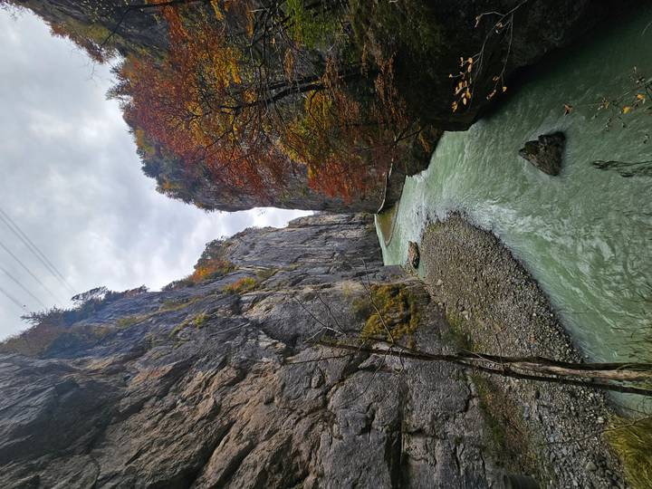 Smalle rivier die door een dramatische kloof stroomt met herfstgebladerte.
