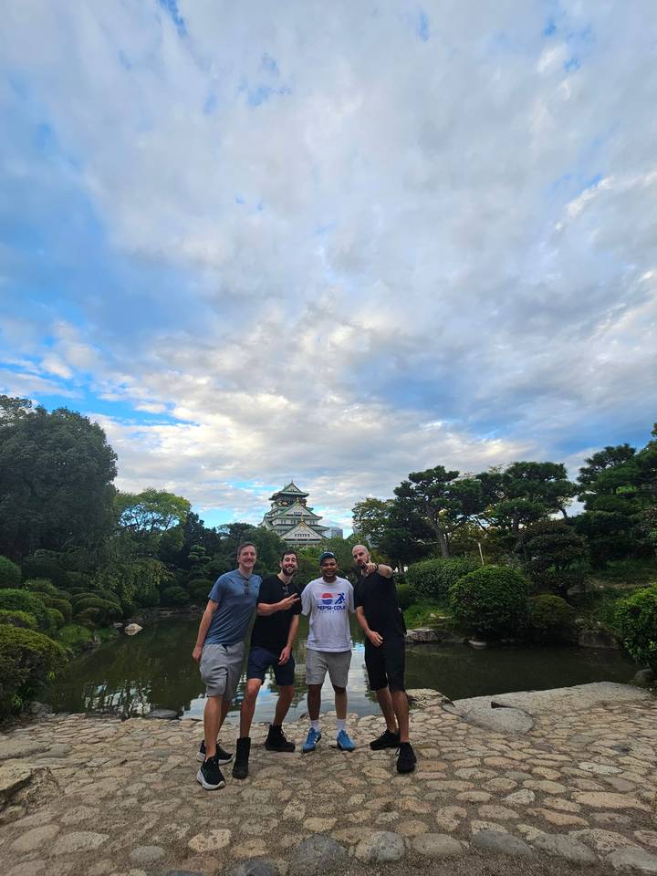 Grupo de personas posando frente a un castillo japonés.