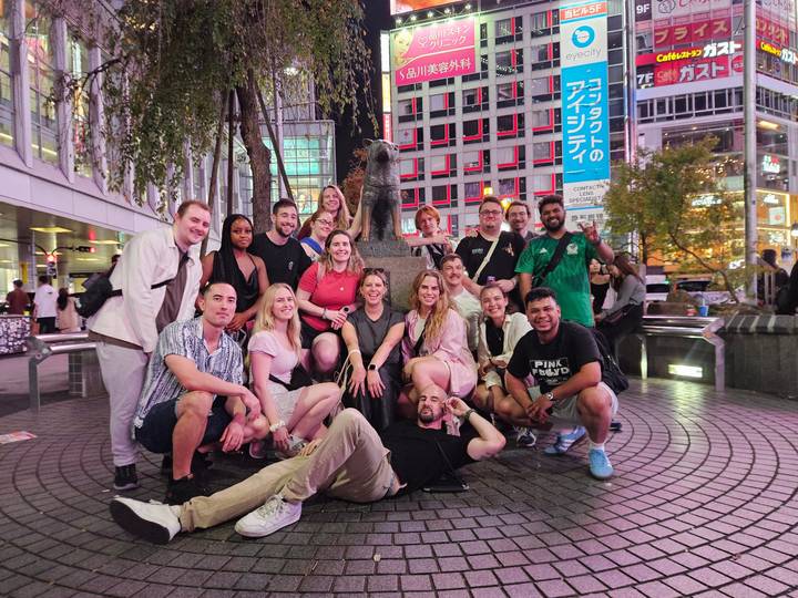 Foto grupal en una intersección concurrida junto a una famosa estatua de perro.