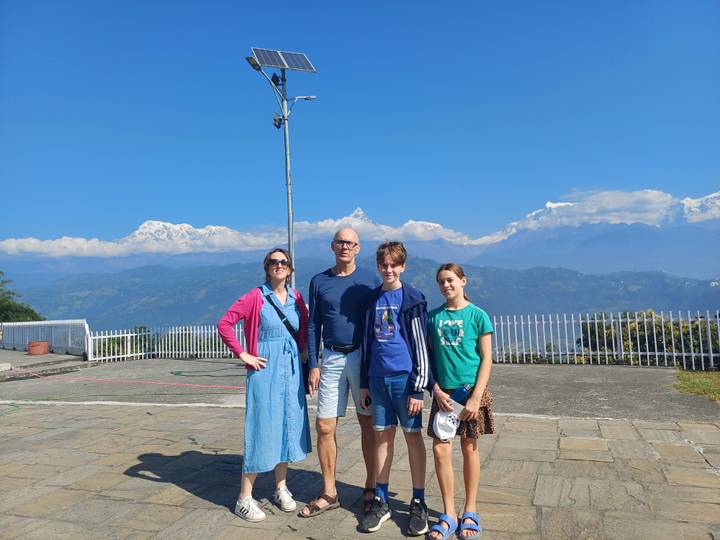 Une famille posant avec un arrière-plan montagneux sous un ciel dégagé.