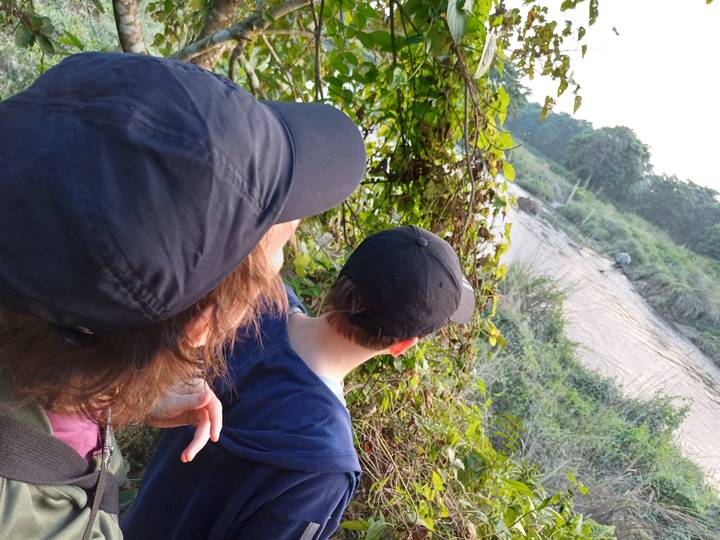 Deux personnes regardant une rivière entourée de végétation.