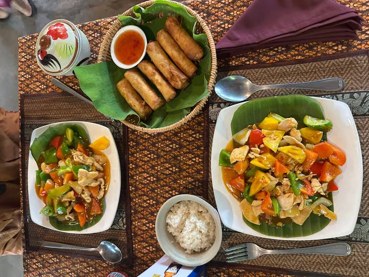 Assiettes de nourriture incluant des rouleaux de printemps et du riz, servies sur une table