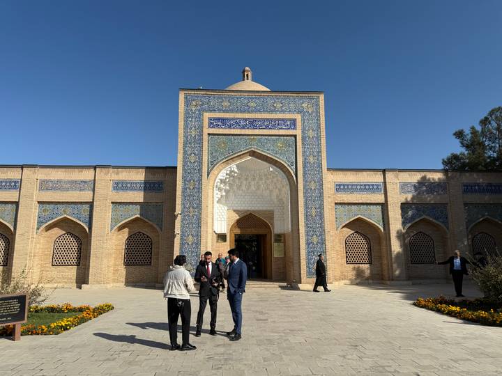Des personnes à l'entrée d'un bâtiment historique avec des motifs bleus ornés.