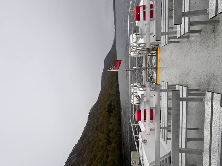 Pont de ferry vide avec un drapeau Union Jack, entouré d'eau calme de lac.