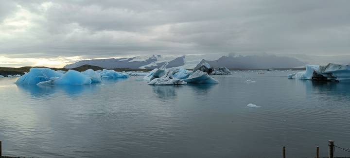Icebergs floating in a glacial lagoon with snowy mountains in the background.