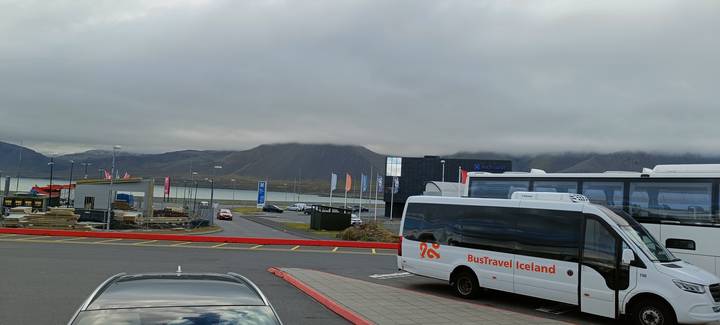 Parking area with buses and overcast sky.