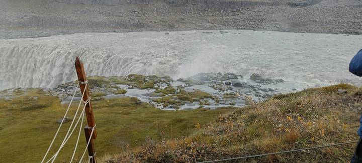 Waterfall with a wooden fence in the foreground.