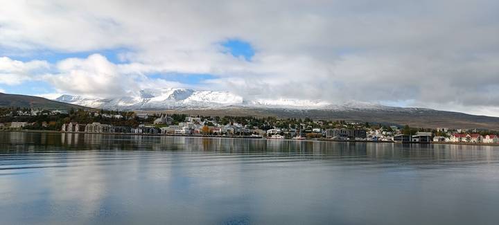 Panoramic view of a town by the water with mountains.