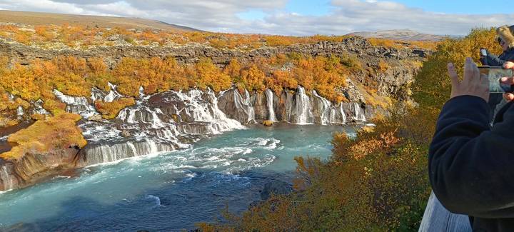 Scenic view of a waterfall surrounded by autumn foliage.