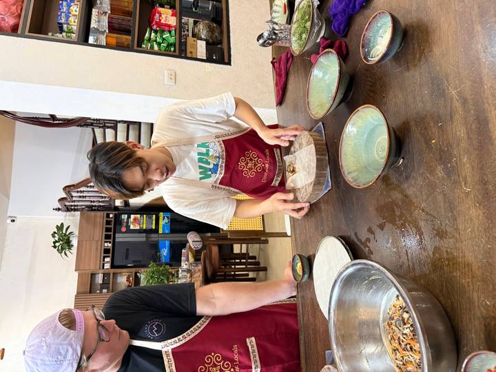 Person, die Essen mit Schüsseln und Zutaten auf einem Tisch zubereitet.