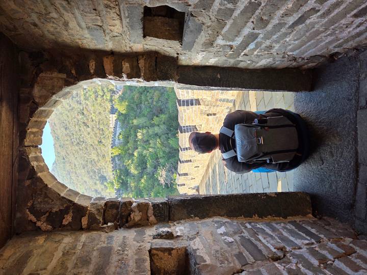 Person sitting at an archway on the Great Wall of China.