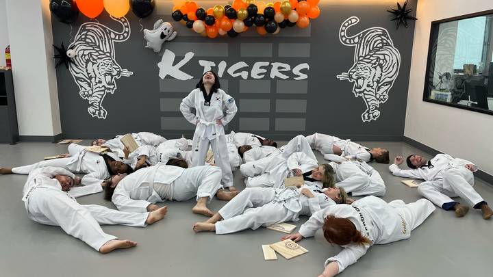 Groep mensen in vechtsportuniformen die speels poseren.