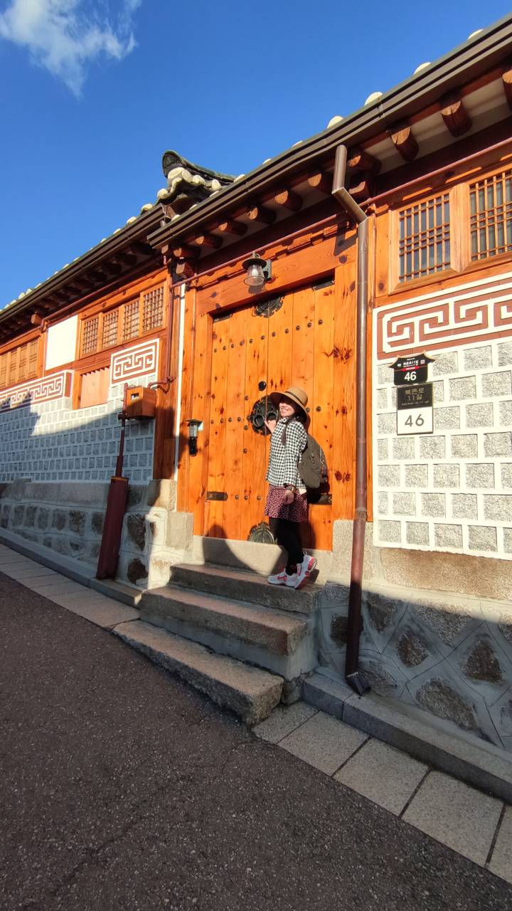 Persoon poseert voor een traditionele houten poort.