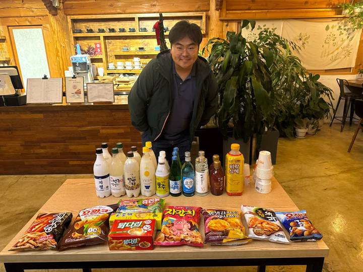 Persoon die een selectie van lokale snacks en drankjes presenteert.