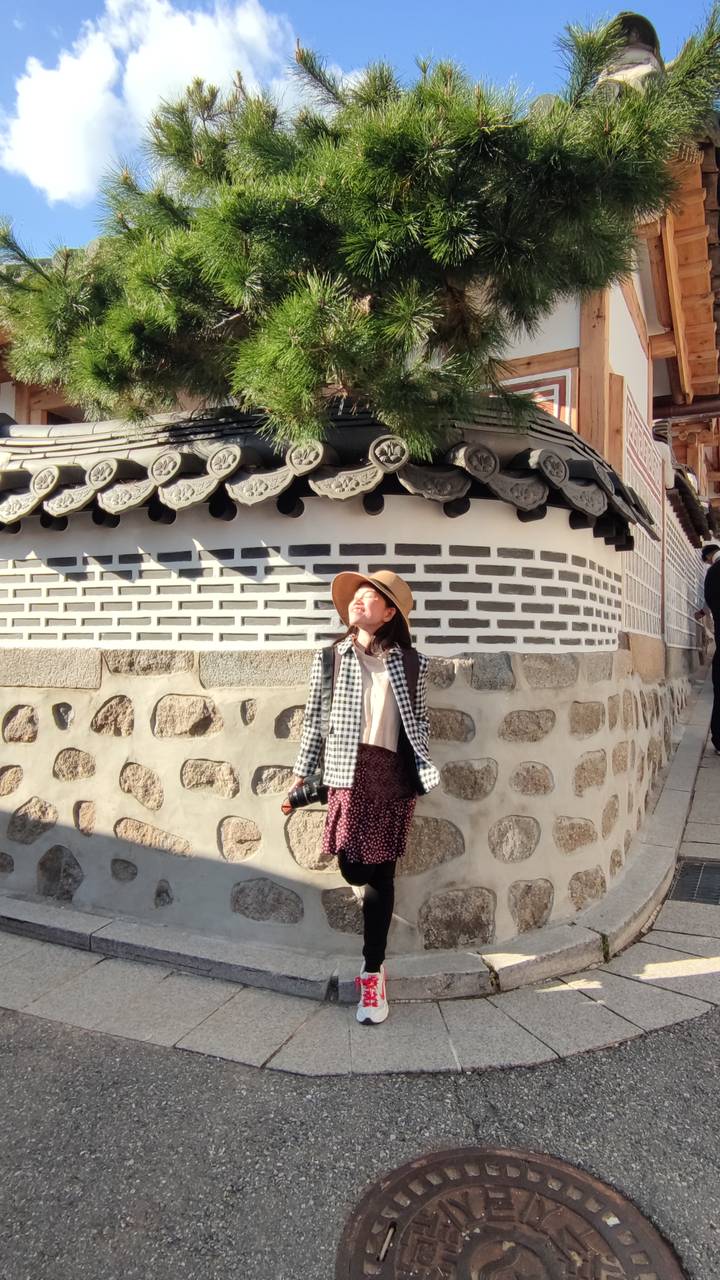 Persoon die van de zon geniet voor een traditioneel Koreaans huis.