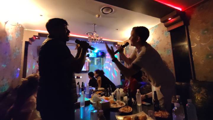 Mensen die genieten van karaoke in een zwak verlichte kamer.