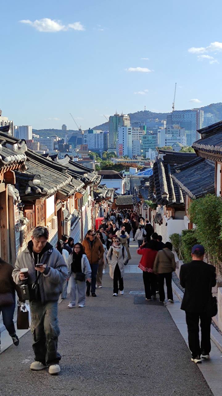 Drukke straat met traditionele huizen en wandelende mensen.