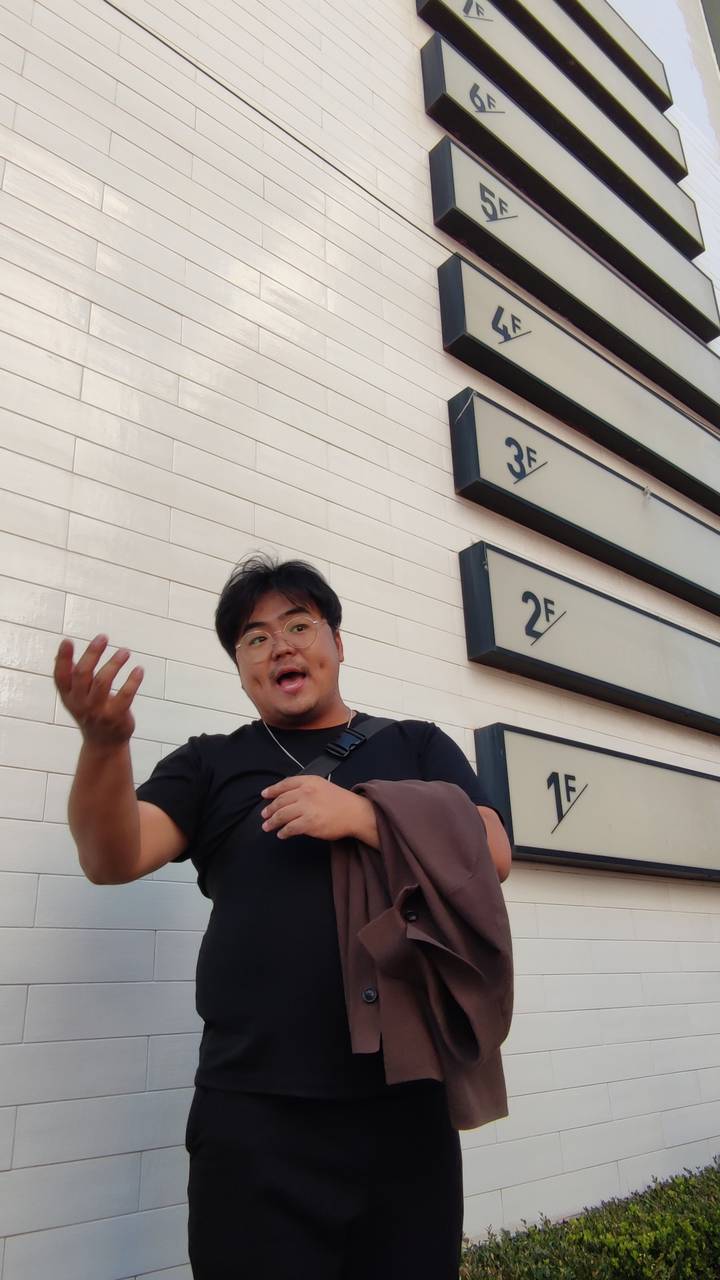 Man die gebaart voor een bord met verdiepingnummers.