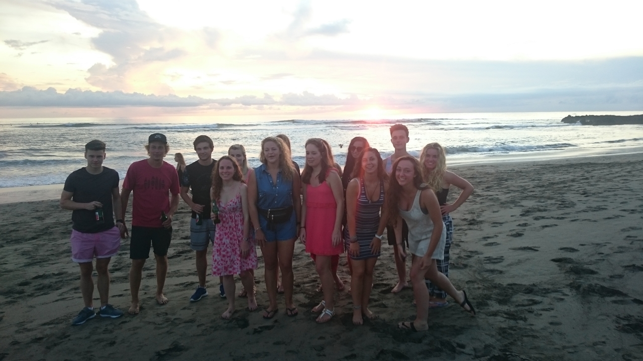 Group of people posing on a beach with a sunset.