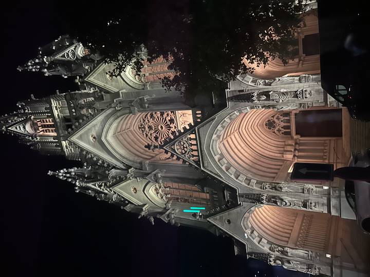 Beleuchtete gotische Kirchenfassade bei Nacht.