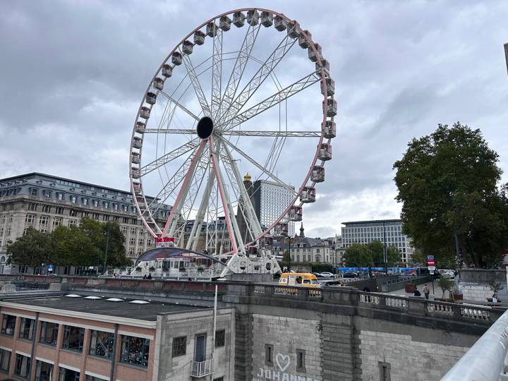 Riesenrad in einer Stadtlandschaft mit bewölktem Himmel.