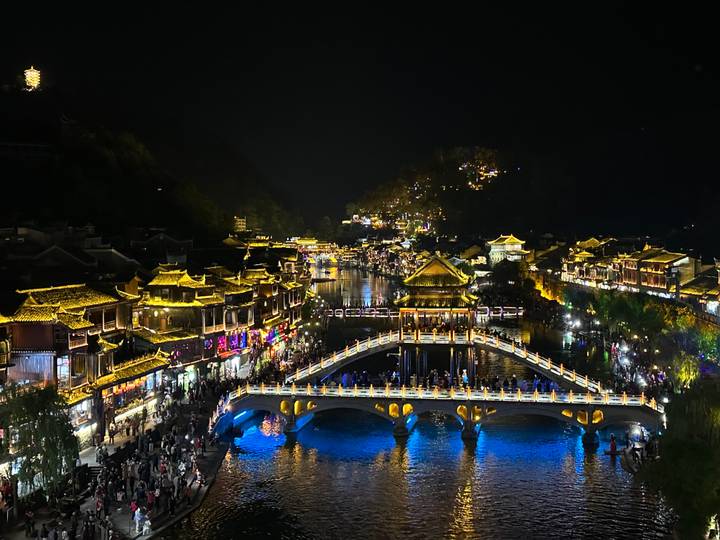 Architecture chinoise traditionnelle illuminée au-dessus d'une rivière la nuit.