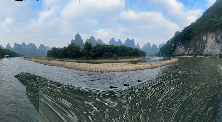 Bateau sur une rivière avec des montagnes karstiques en arrière-plan.
