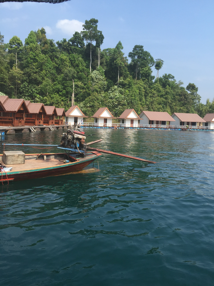 Traditional boat on water with houses in the background.