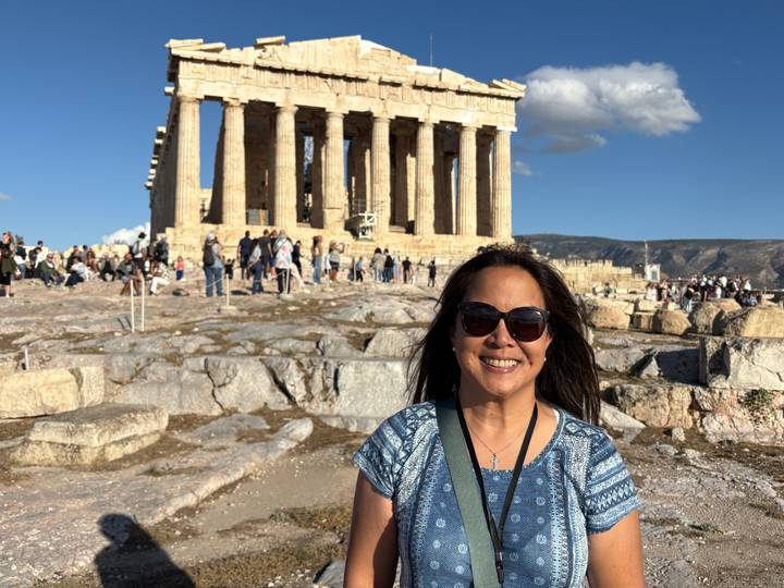 Tourist posiert vor dem Parthenon mit anderen Besuchern im Hintergrund.