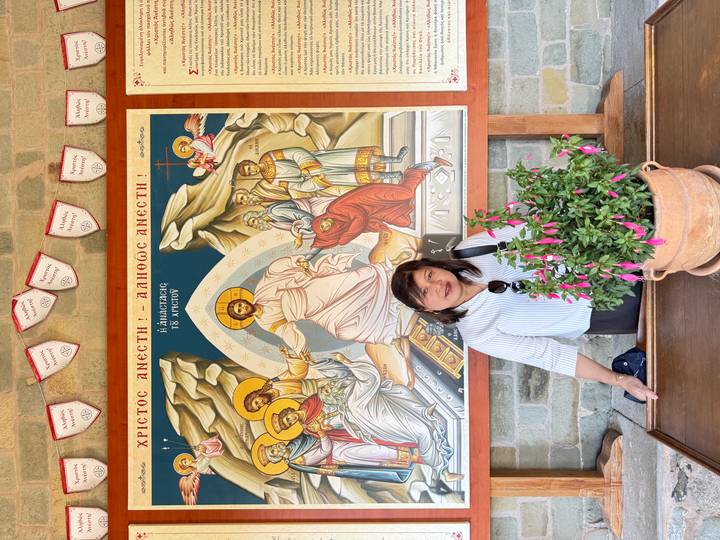 Frau, die vor einem religiösen Wandgemälde steht.