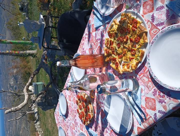 Table d'extérieur dressée avec des assiettes de nourriture et des boissons sur fond de campagne.
