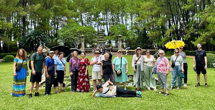 Gruppe von Touristen, die in einem Parkbereich mit Bäumen posieren.