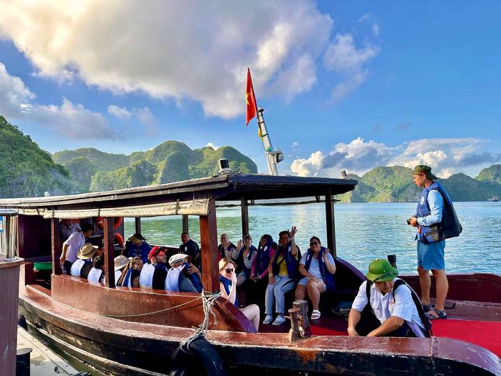 Touristen auf einem Boot in einer malerischen Bucht mit Hügeln.