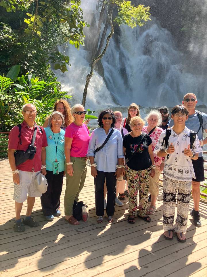 Reisegruppe vor dem Hintergrund eines Wasserfalls.