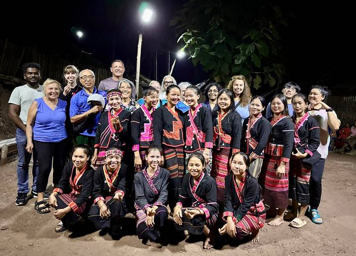 Gruppe von Touristen mit einheimischen Künstlern in traditioneller Kleidung.