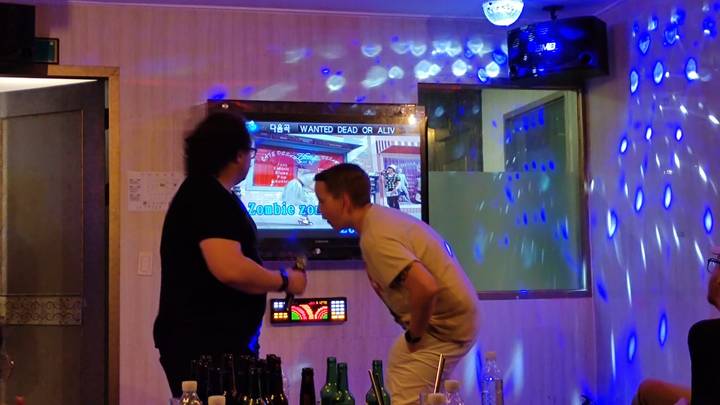 Twee mensen in een karaoke-omgeving met kleurrijke lichten.