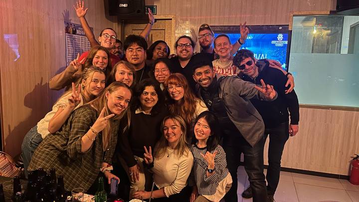 Groep mensen die samen poseren in een binnenruimte met vrolijke gezichtsuitdrukkingen.