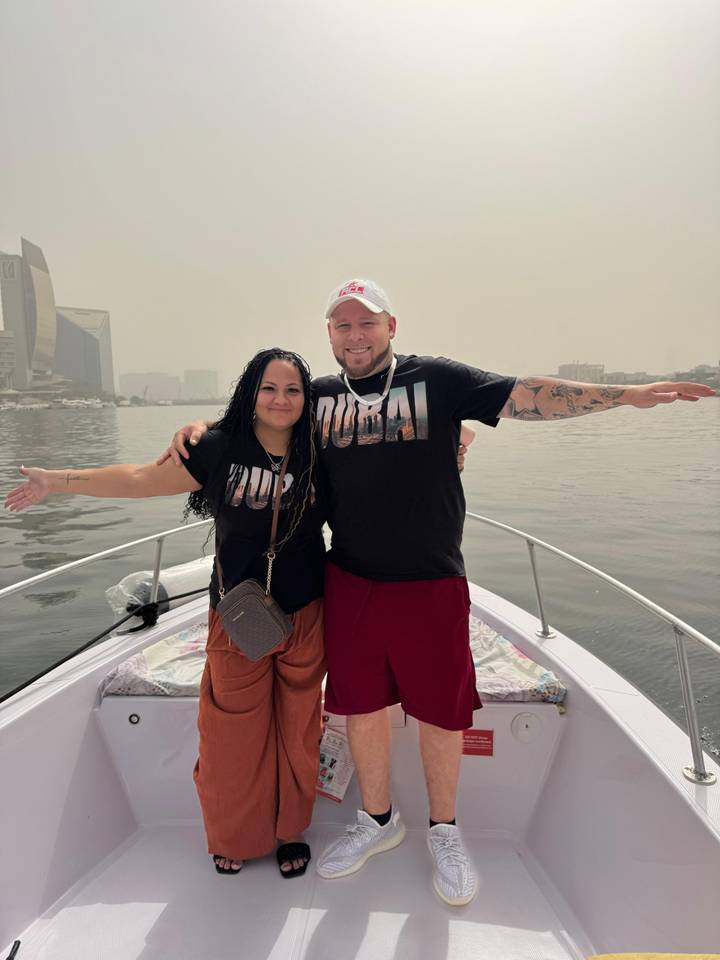 Couple posant sur un bateau avec l'horizon de la ville en arrière-plan.