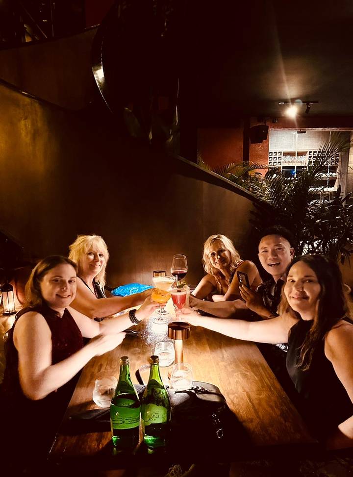 Gruppe von Menschen, die in einer schwach beleuchteten Bar anstoßen.