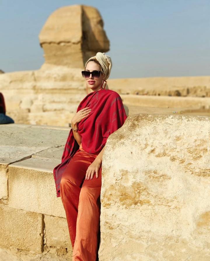 Person in red attire sitting near ancient ruins.